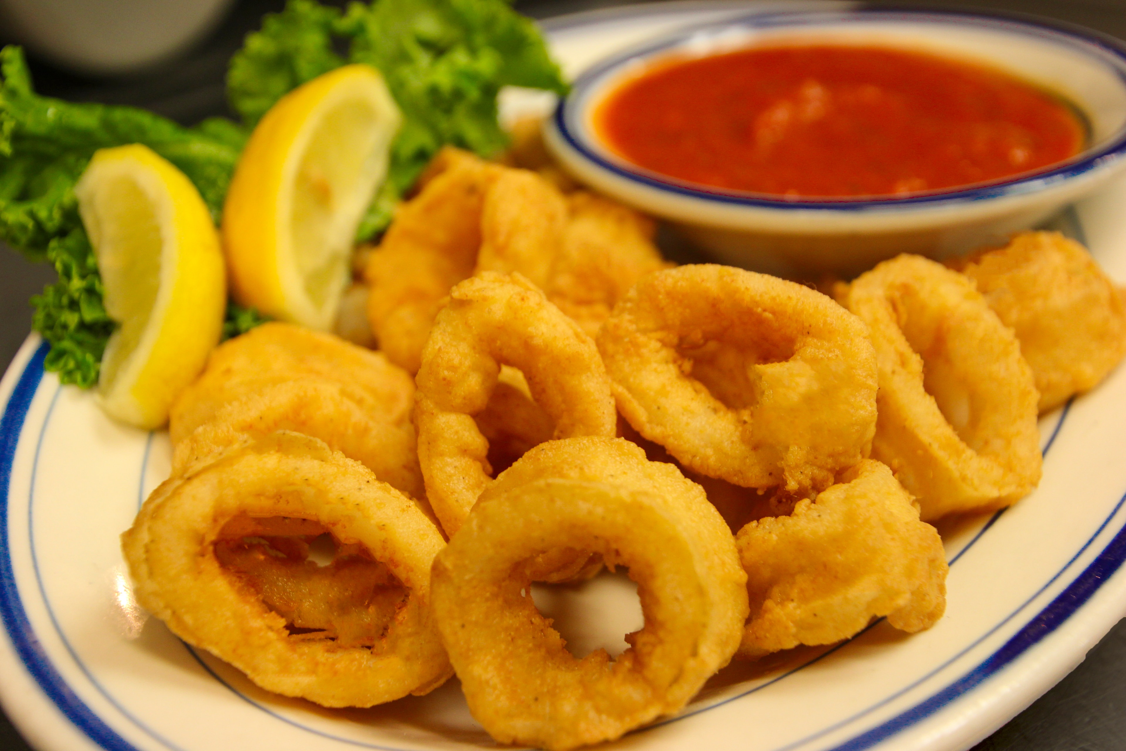 Golden fried calamari rings with marinara dipping sauce and lemon wedges