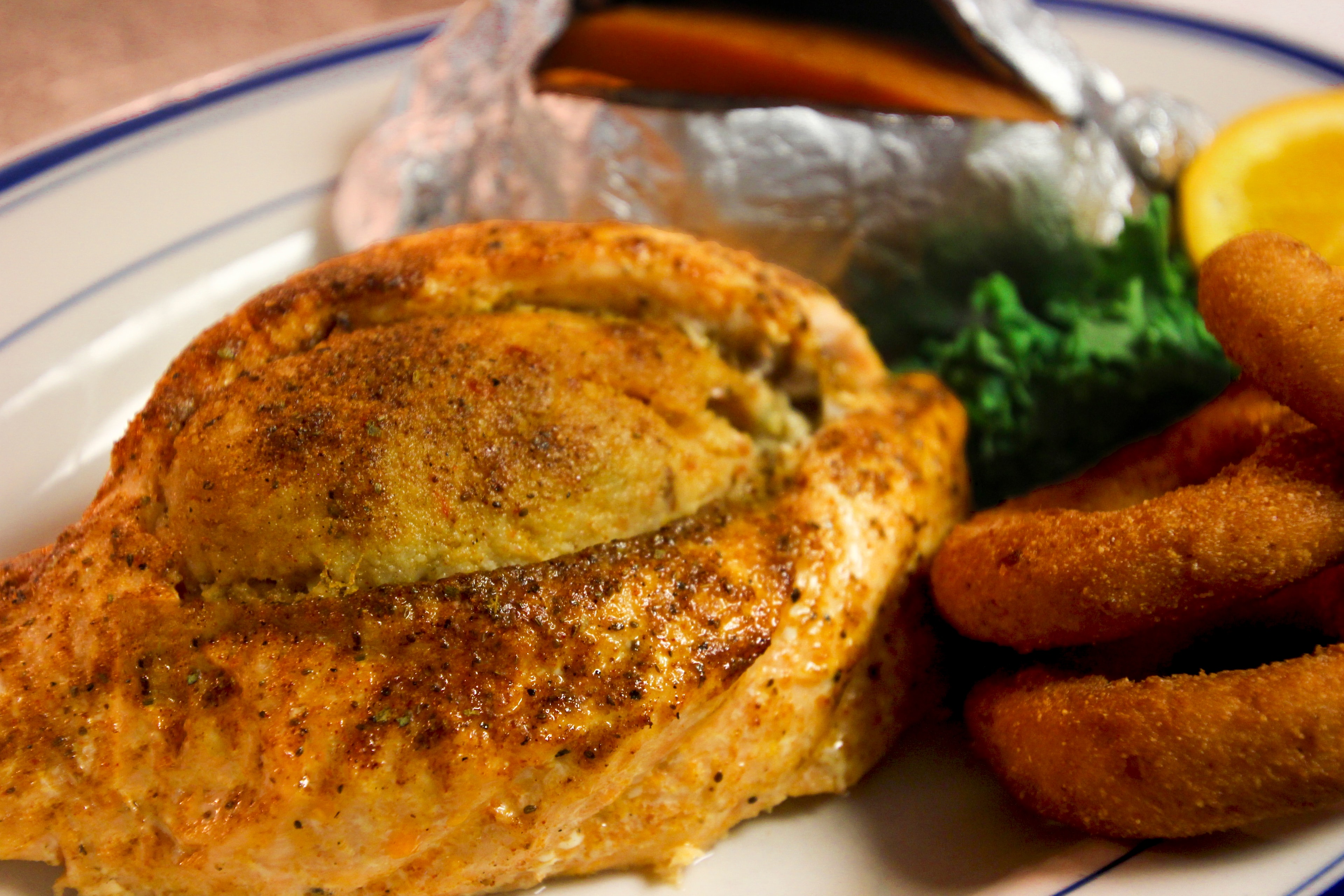 Stuffed salmon fillet with seasoned crab stuffing, broccoli, hushpuppies, and baked potato